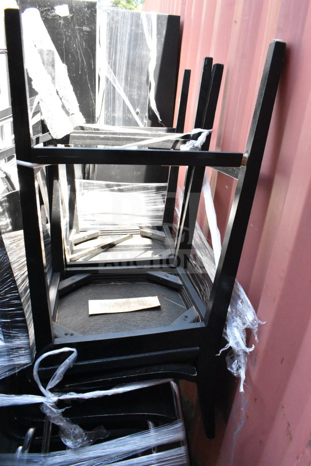 Stack of 11 black dining chairs, new condition, sleek design, with attached packaging for protection. Auction lot detail tag visible.