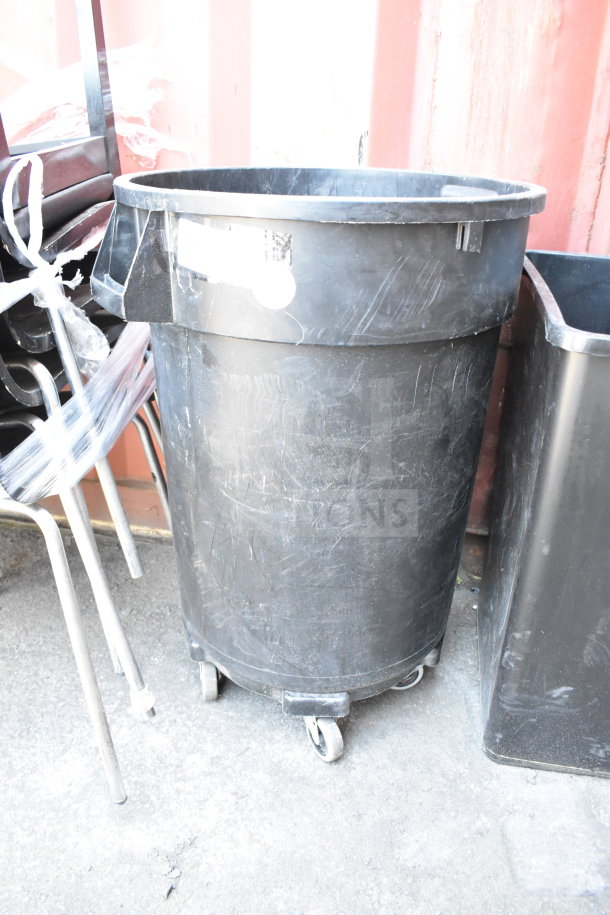Three various black trash cans on wheels, used condition, outdoor setting.