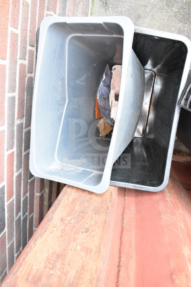 Three assorted trash cans stacked, showing signs of use. Gray and black plastic, suitable for indoor or outdoor use.