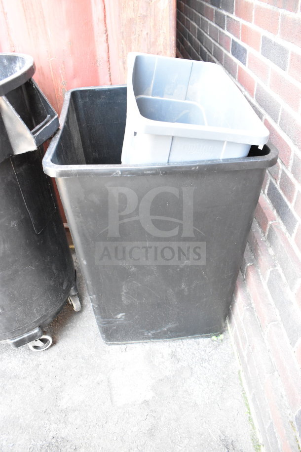 Three various black and gray trash cans, with one on wheels. Used condition, suitable for waste management.