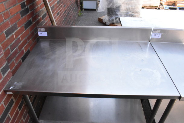 Winholt stainless steel commercial table with backsplash and undershelf. Slight surface wear visible. Labels indicate item number.