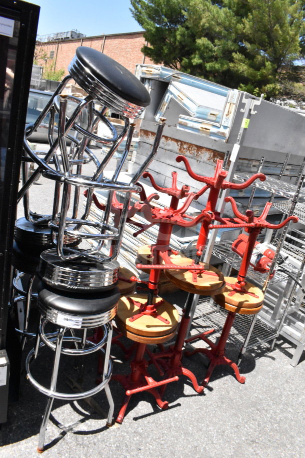 15 assorted stools in varying styles, including chrome bar stools and red industrial stools, stacked outdoors.