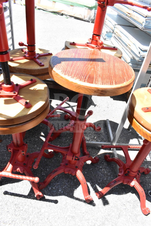 15 rustic wooden stools with red metal bases; sturdy, adjustable design, ideal for industrial-themed interiors.