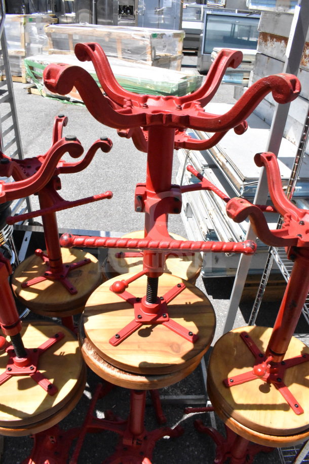 15 red metal and wood stools with adjustable seats, used condition. Unique spiral design on bases, suitable for industrial decor.