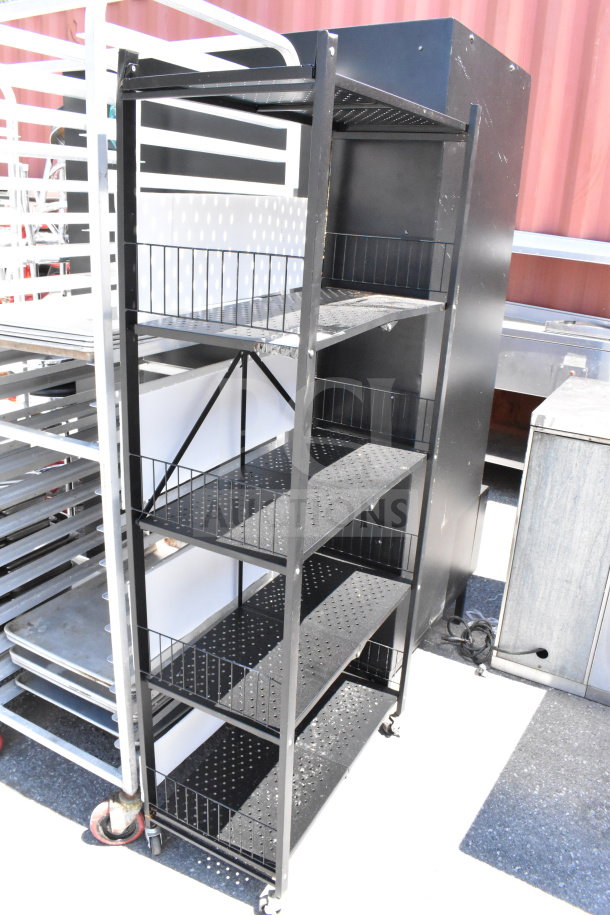 Black metal shelving unit with five perforated shelves, commercial casters for mobility, in good condition.