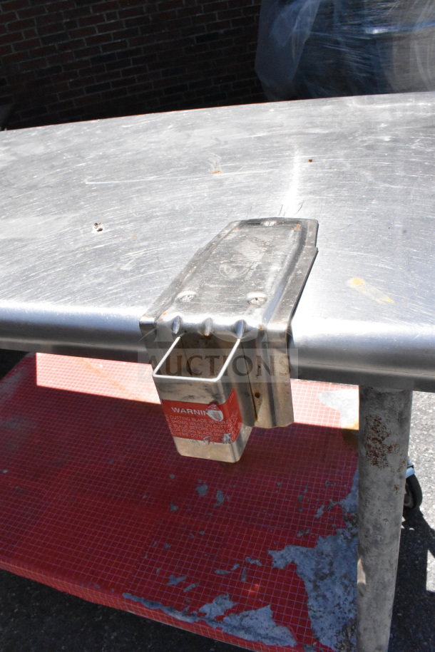 Commercial metal table with under shelf, can opener mount, on casters; visible wear and rust on surfaces.