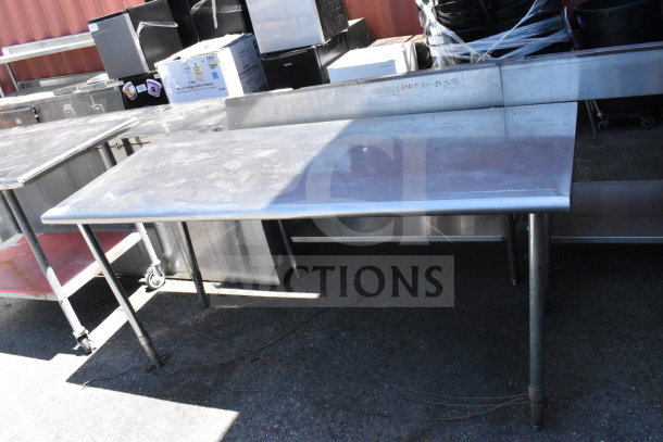 Stainless steel commercial table with sturdy legs and visible wear, ideal for industrial kitchen use.