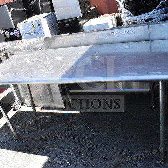 Stainless steel commercial table with sturdy legs and visible wear, ideal for industrial kitchen use.