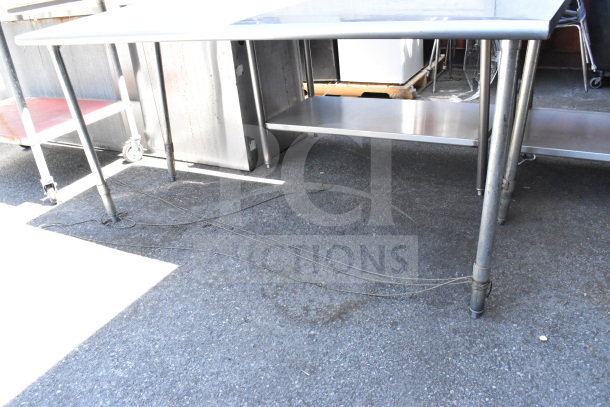 Commercial table with a stainless steel top and sturdy metal legs, featuring a lower shelf. Good condition, suitable for industrial use.
