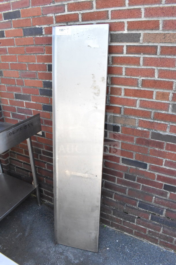 Metal shelf leaning against a brick wall. Slightly worn condition with visible marks. Tag reads "155".