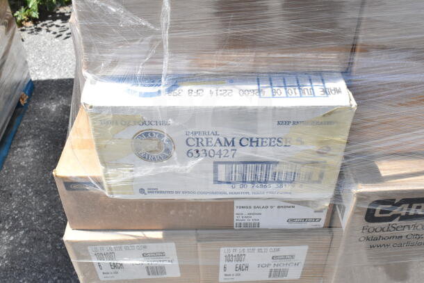 Boxes of Carlisle tongs, lids, and tumblers. Labels show item details. Items wrapped on a pallet, ready for auction.