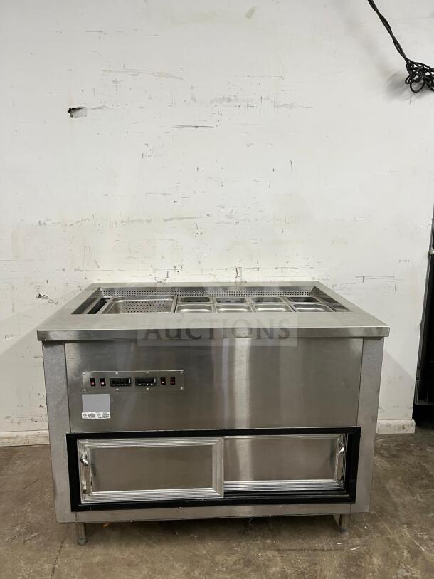 Stainless steel prep table with salad bar, dual controls, cooling unit, and storage. Excellent condition.