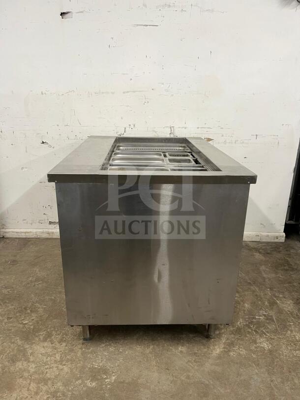 Stainless steel prep table with salad bar, multiple compartments, good condition, durable and versatile for culinary use.