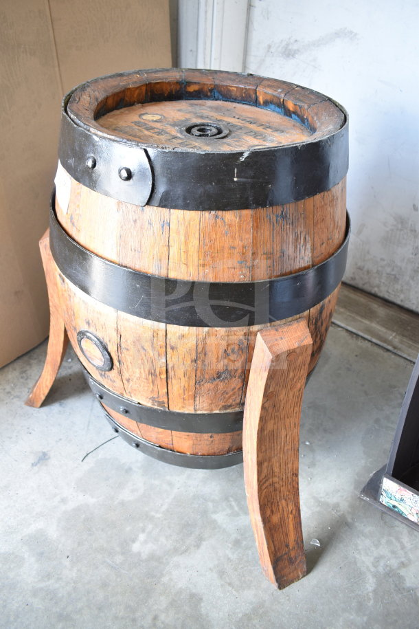 Vintage wooden barrel with black metal bands, visible wear, and a wooden stand. Ideal for decor or storage.