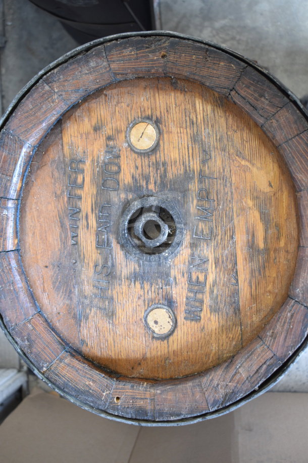 Wooden barrel with metal rims, marked "WINTER" and "WHEN EMPTY," showing aged patina. Center bunghole visible.