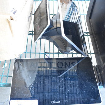 Two Toast POS monitors on a metal rack, showing black screens. Condition appears used, with small visible marks.