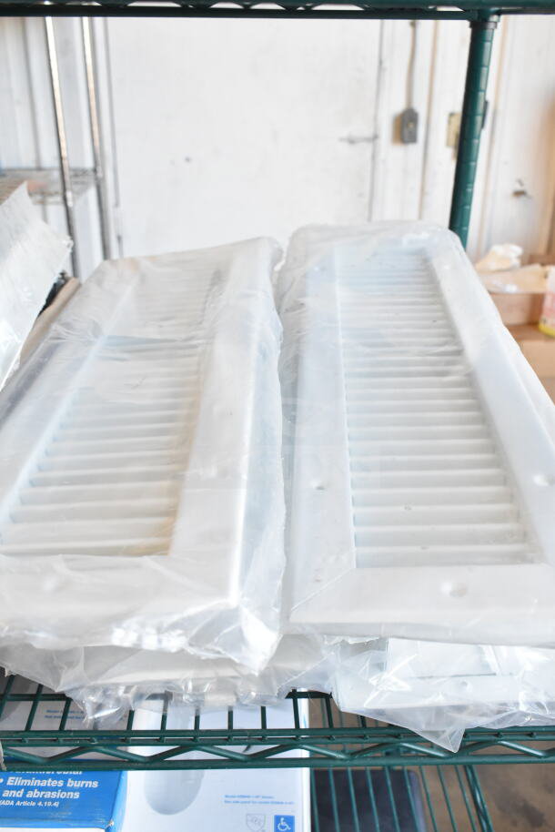 10 packaged vent covers in new condition, white plastic material, displayed on shelving.