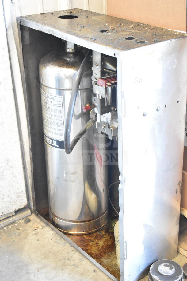 Ansul fire suppression system box with tank, visible wear and rust. Labels show Ansul branding and operational details.