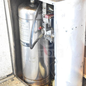 Ansul fire suppression system box with tank, visible wear and rust. Labels show Ansul branding and operational details.