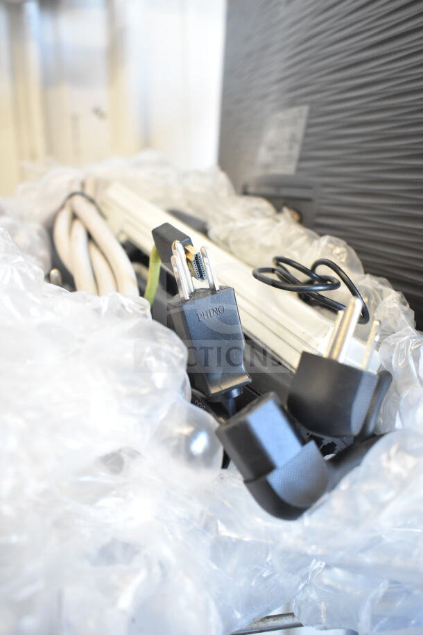 Assorted electronics including POS monitors, cables, and accessories in a plastic wrap; power plug labeled "PHINO."