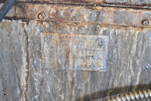 Rusted label on commercial equipment detailing specifications, including model and energy use, partially obscured by corrosion.