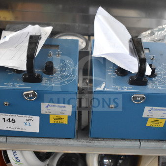 Two blue GA-100 radon monitors with handles and dials, labeled for auction.