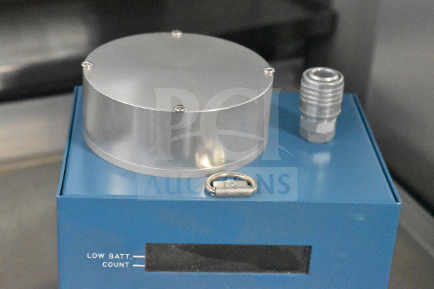 Blue GA-100 Radon Monitor with metal cylinder and gauge, featuring low battery and count indicators. Appears in good condition.