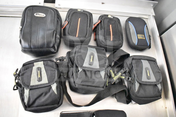 Nine camera bags with two cameras including Nikon Coolpix and Garmin Nuvi. Various sizes, mostly black with brand logos.