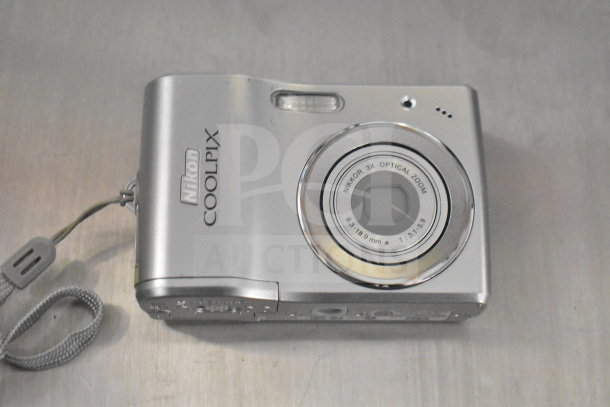 Nikon Coolpix camera with 3x optical zoom, silver finish, includes 9 camera bags and Garmin Nuvi. Auction value pack.
