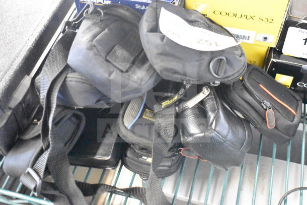 9 camera bags with Nikon Coolpix and Garmin Nuvi visible. Varied styles, zippers, tags. Each adds value to the auction lot.