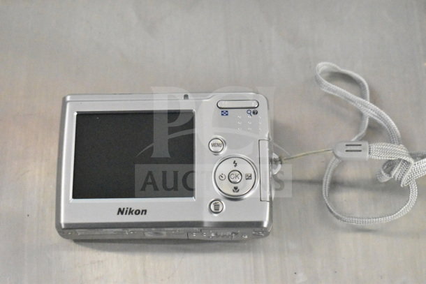 Nikon Coolpix camera with grey wrist strap, rear view showing screen and buttons.