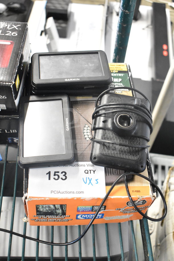 5-item lot with 4 Garmin GPS units and a Bushnell Trail Camera. Visible wear; Bushnell box indicates model and night vision feature.