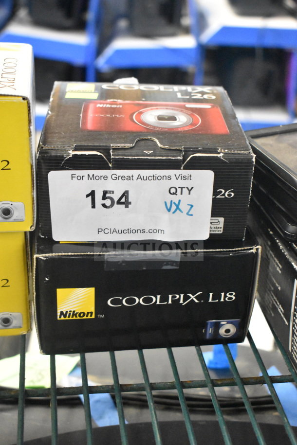 Nikon Coolpix L18 and L26 digital cameras in original boxes. Auction label: 154, "2 Times Your Bid!"