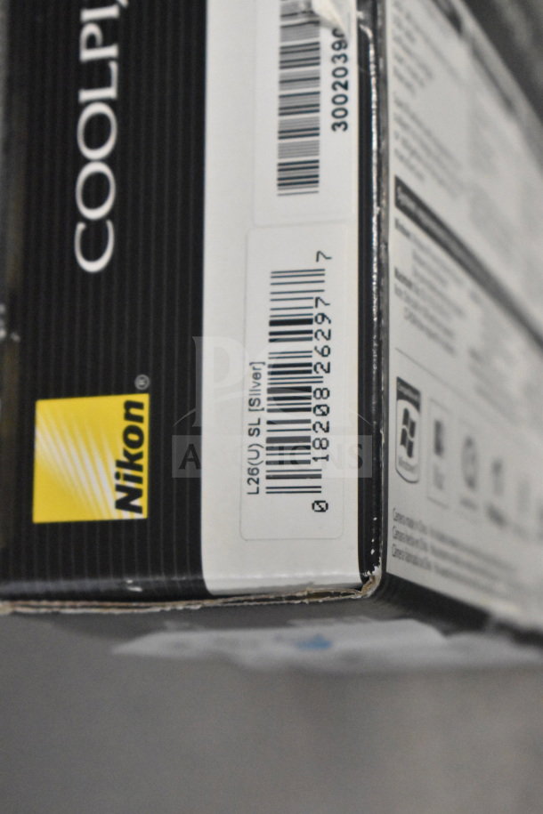 Nikon Coolpix L18 and L26 digital cameras in original box. Box shows Nikon branding and barcode for the L26 model.