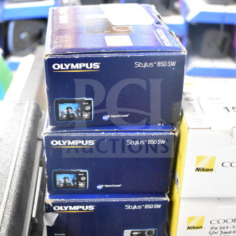 Three Olympus Stylus 850 SW digital cameras in original boxes. Boxes show brand and model info; feature HyperCrystal display.