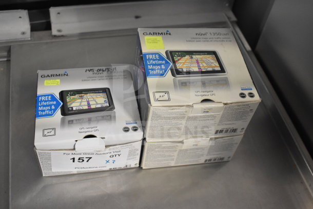 Three Garmin GPS devices in original boxes, including Nuvi 1350 and Nuvi 1390 models, featuring free lifetime maps.