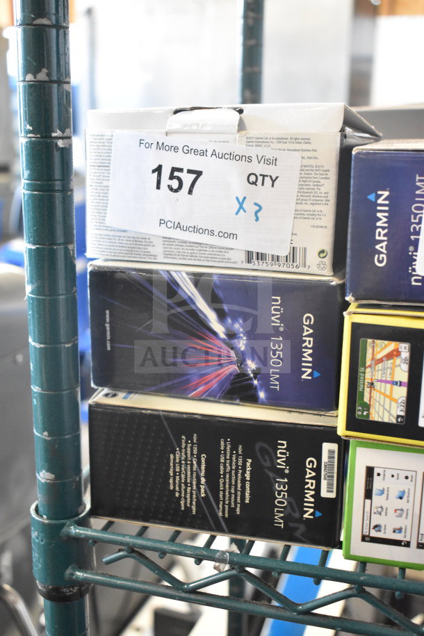 Three Garmin GPS units in original boxes, including Nuvi 1350 and Nuvi 1390, on auction shelf with tag.