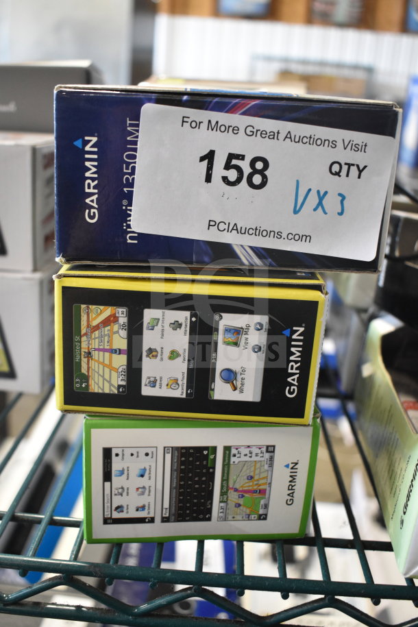 Three Garmin GPS devices, models Nuvi 55, Nuvi 40, Nuvi 1350, in original boxes. Auction tag visible.