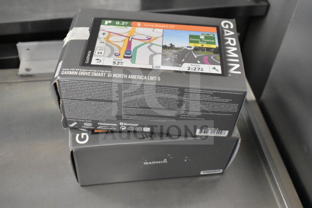 Three Garmin DriveSmart 61 LMT-S GPS units in original boxes, featuring North America maps and Bluetooth connectivity.