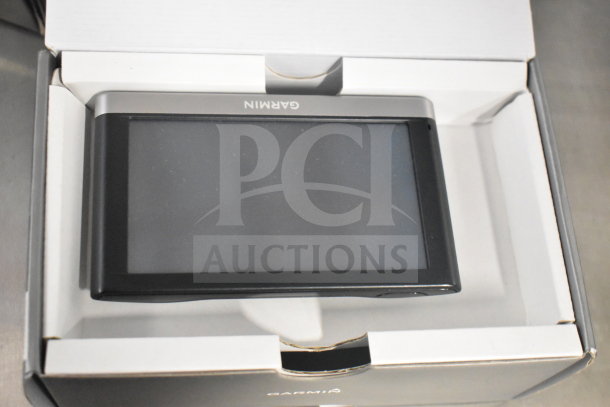 Garmin GPS in original box, pristine condition, includes three units. Brand logo visible, ideal for precise navigation.