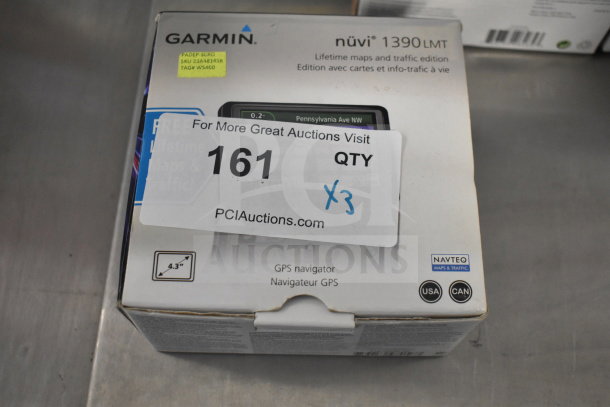 Box of Garmin GPS devices: eTrex Legend H, eTrex 20, Nuvi 1390LMT. Visible label shows quantity of three, new condition.