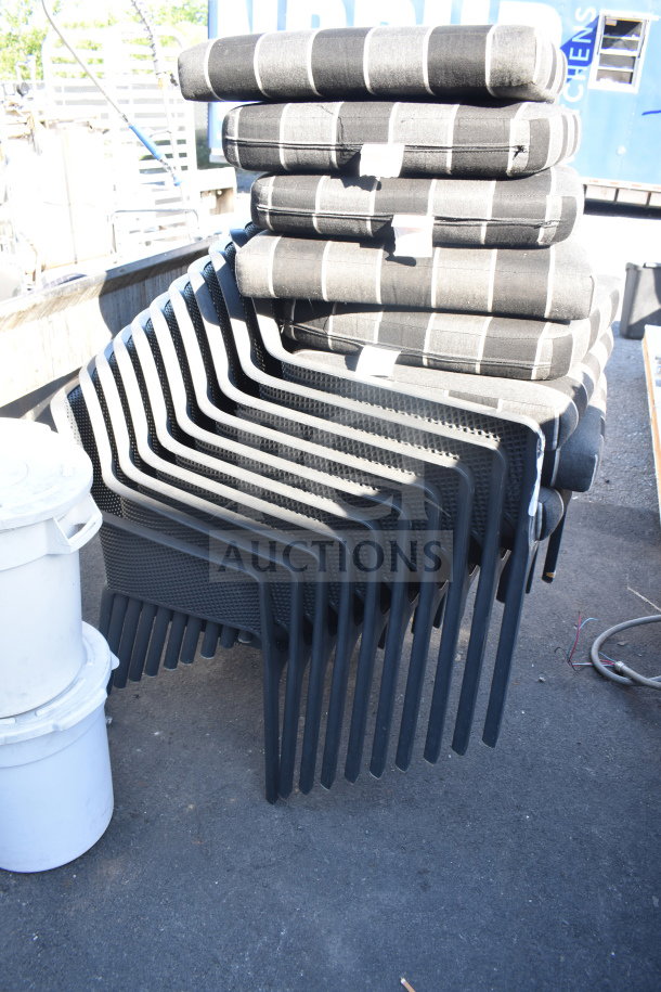 17 black patio arm chairs, stacked with gray and black cushions, showing excellent condition for auction.