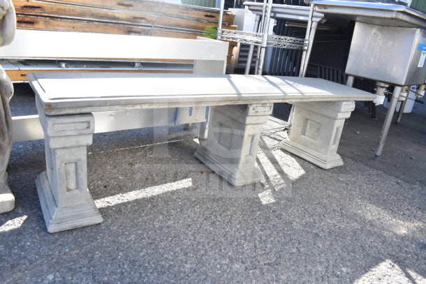 Stone bench with decorative pedestal legs, concrete statue partially visible. Used condition, ideal for garden decor.