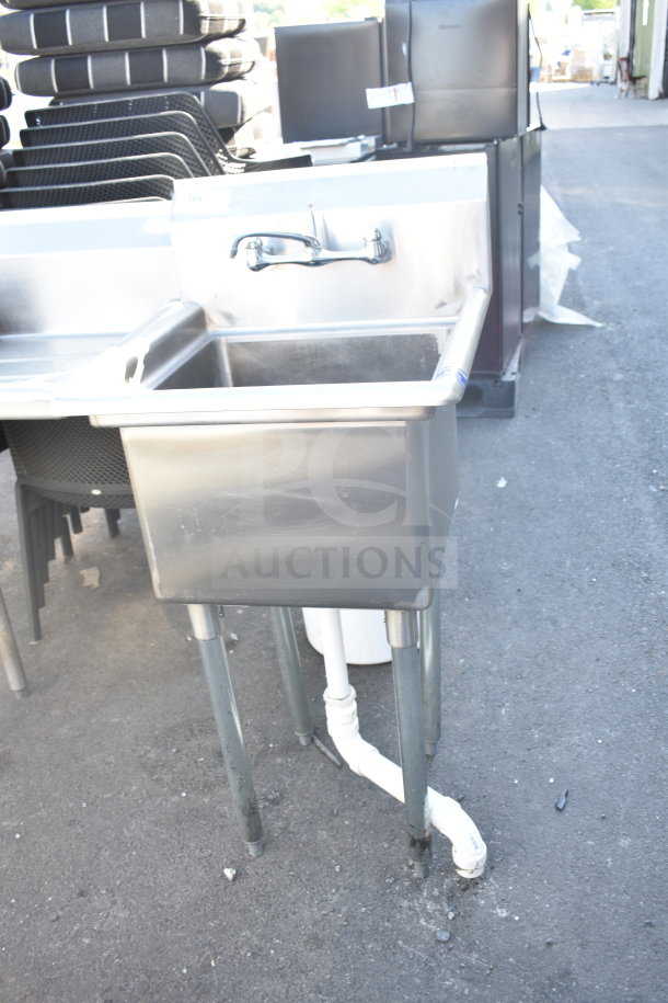 Stainless steel commercial single bay sink with faucet, displaying minimal wear, sturdy metal legs, visible plumbing beneath.