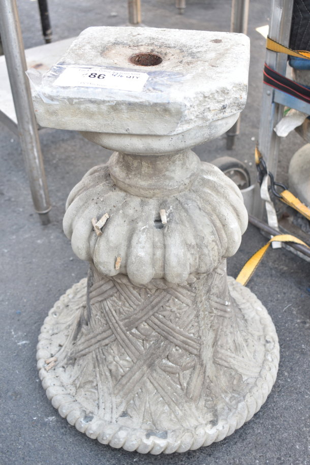Ornate stone planter with carved details and worn surface, featuring a square top with a central hole. Auction tag visible.