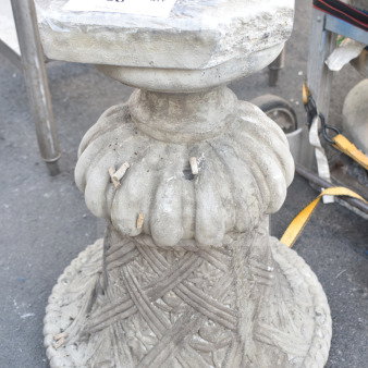 Ornate stone planter with carved details and worn surface, featuring a square top with a central hole. Auction tag visible.