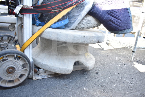 Stone statue base, securely wrapped and strapped on a dolly. Marked "973" indicating lot number. Good condition, outdoor setting.