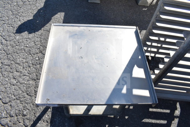Commercial equipment stand with under shelf, made of stainless steel. Surface shows minor wear. Ideal for storage.
