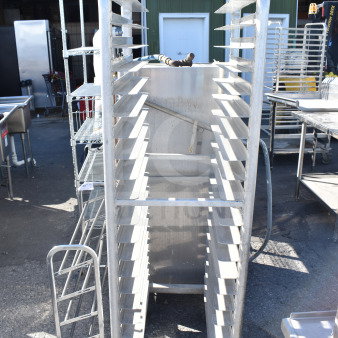 Commercial pan transport rack with multiple shelves on sturdy commercial casters, in good condition for efficient mobility.