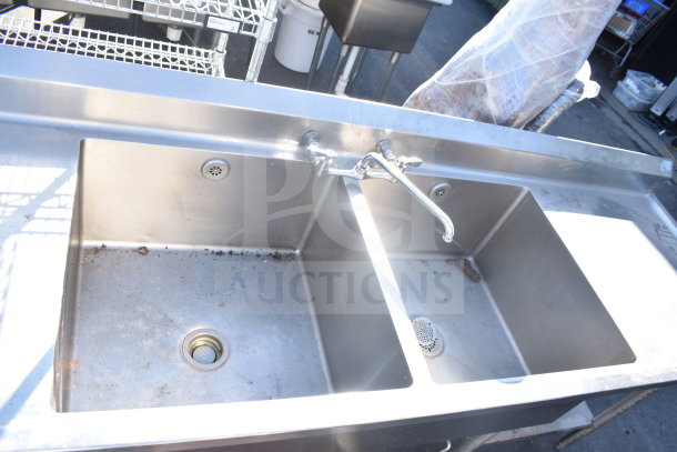 Commercial 2 bay sink with dual drain boards, stainless steel, dual faucet, visible wear, ideal for restaurant use.